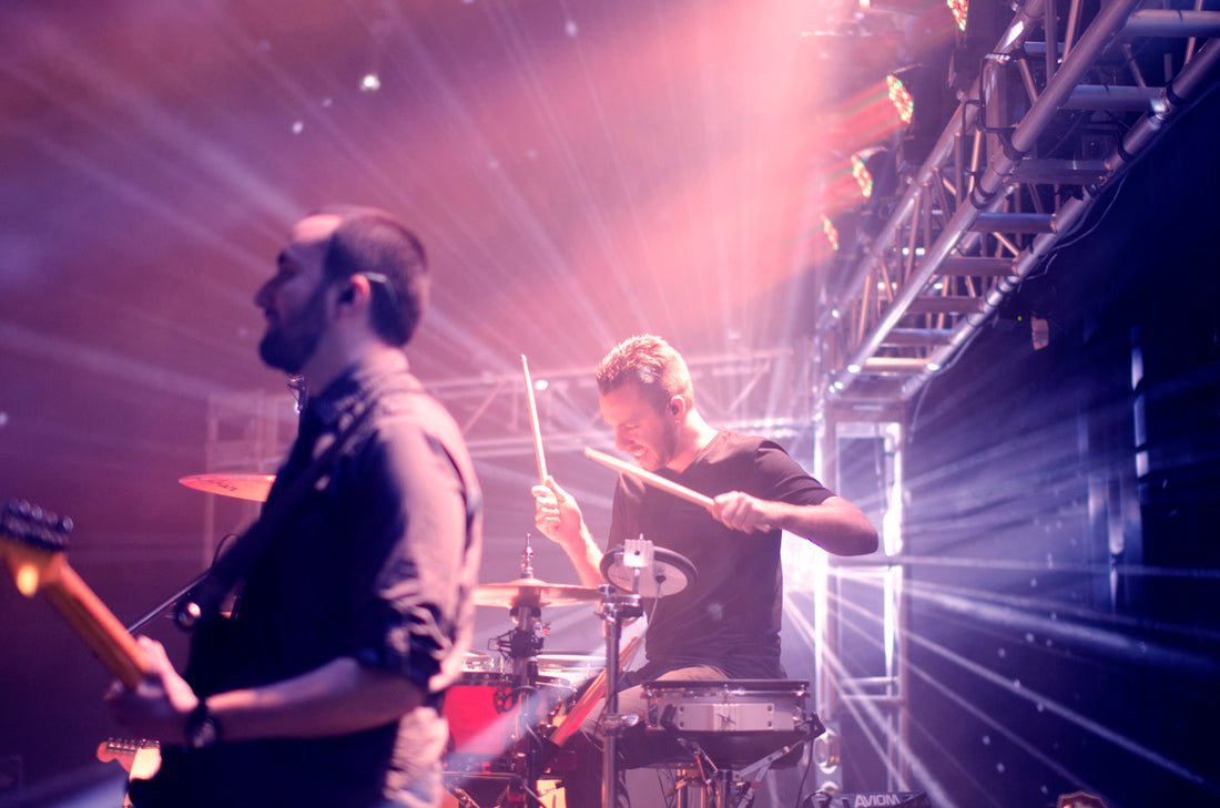 Drummer performing on stage under intense concert lights